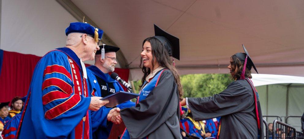 A student shaking hands with a faculty member at commencement